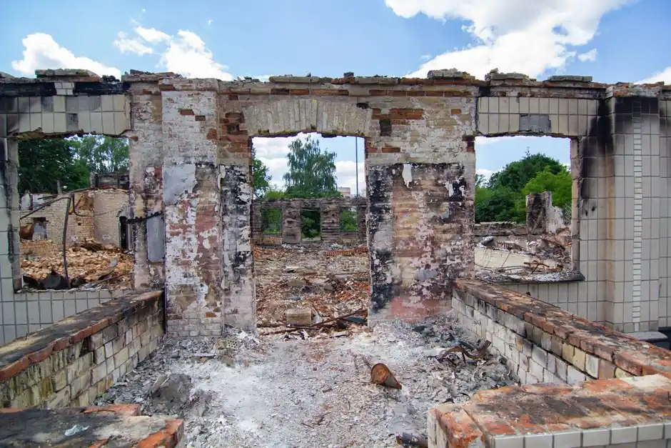 A deteriorated brick structure with clear skies, showcasing decay and natural reclamation.