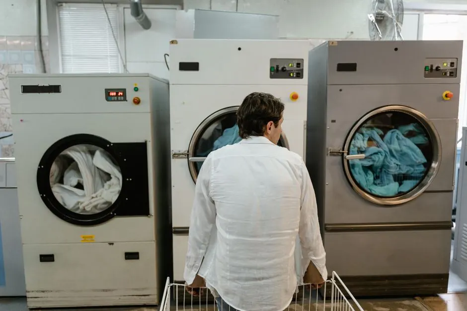A man uses commercial washing machines at an indoor laundromat.