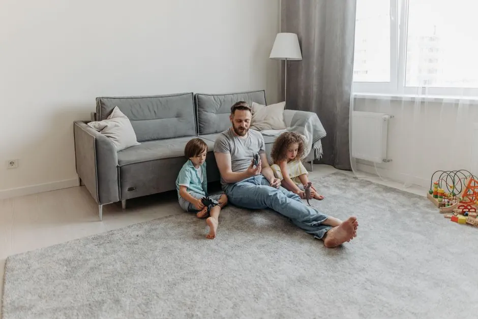 Father and two children enjoy playtime in the living room. Warm family bonding moment captured indoors.